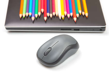 wireless computer mouse on the background of a laptop with colored pencilsの写真素材