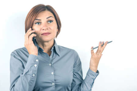 Business beautiful woman speaks on the phone with a pencil in her hand on a white backgroundの写真素材