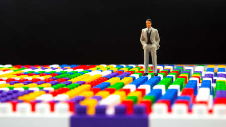 miniature people. figure of a man stand near the colored plastic blocks of the game constructor. concept of business and industrial development. the concept of dreams and choice of life directionの写真素材