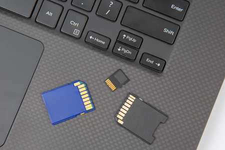 sd memory card for recording electronic data near a laptop on a white background. electronic...