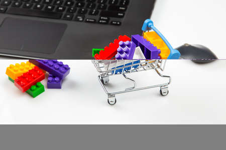 shopping cart with plastic colored constructor blocks on laptop background. online shopping business