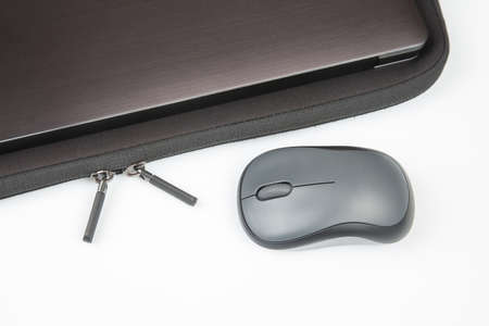 Computer wireless mouse next to a laptop on a white table close-up. electronic personal industry