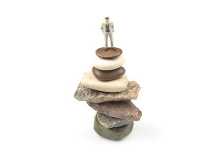 miniature people. the figure of a man stands on top of the stones. concept of achievements in life...