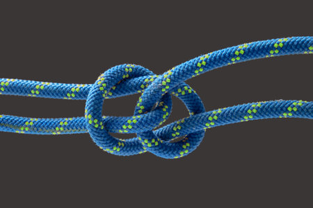 durable colored rope for climbing equipment on a dark background. knot of braided cable. item for...