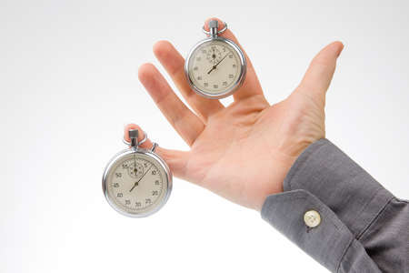 Two mechanical stopwatches hang on the fingers of a male hand. Time part precision. Measurement of...
