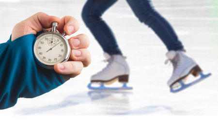 measuring speed on skates with a stopwatch. hand with a stopwatch on the background of the legs of a...