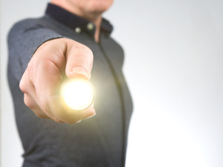 man holds a flashlight in his hand. item for camping and household lifeの写真素材