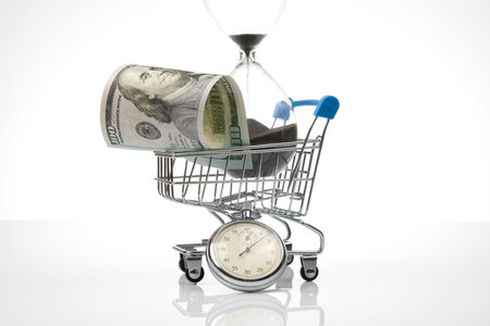 hourglass and dollars in a supermarket basket. buying food and goods. business for sale. saving...