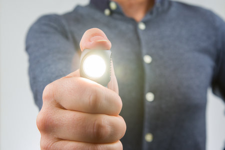man holds a flashlight in his hand. item for camping and household lifeの写真素材