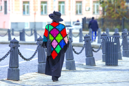 elegant woman in a colored coat walks along the city streetの写真素材