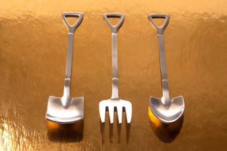 decorative fork and spoons in the form of spades on a golden background. food tools.の写真素材