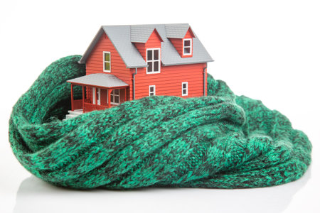 house model is insulated with a knitted scarf on a white background. the concept of keeping warm and cozy indoors at home. cold protectionの写真素材