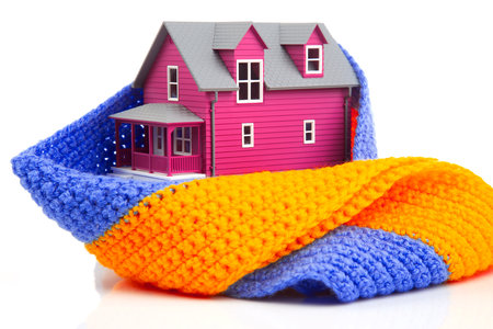 house model is insulated with a knitted scarf on a white background. the concept of keeping warm and cozy indoors at home. cold protectionの写真素材