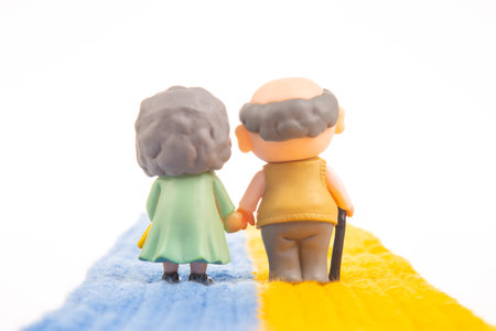 miniature people. figures for the concept. a couple of pensioners people walk together on the Ukrainian flag roadの写真素材