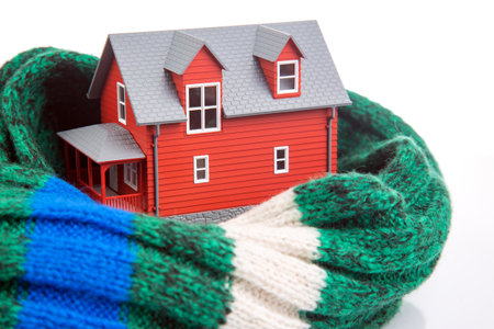 house model is insulated with a knitted scarf on a white background. the concept of keeping warm and cozy indoors at home. cold protectionの写真素材