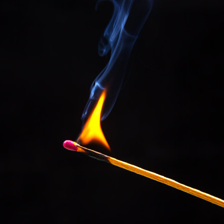 Flashed and burning wooden match on a dark background close-up. Bright fire and smoke from a burning...