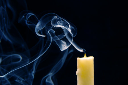 Smoke from an extinguished candle on a dark background. The concept of spirituality and the end of life.の写真素材