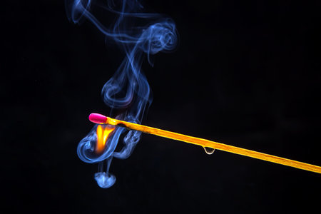 Flashed and burning wooden match on a dark background close-up. Bright fire and smoke from a burning tree.の写真素材