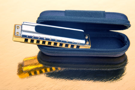 The harmonica lies on a mirrored surface. Classical musical wind instrument.の写真素材