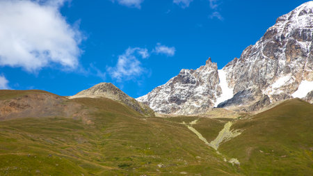 landscape of green grass and snowy mountains. Trekking and travel in Georgiaの写真素材