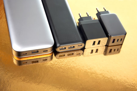 Power bank and charging plug on a golden background. Electronic devices for charging gadgets