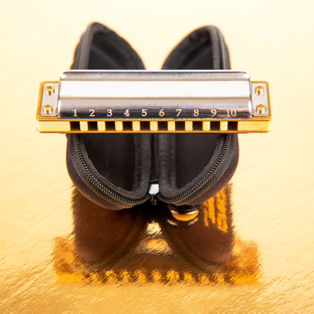 The harmonica lies on a mirrored surface. Classical musical wind instrument.
