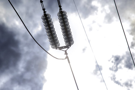 High voltage tower with electrical voltage wires isolates close-up against the background of clouds....