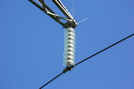 High voltage tower with electrical voltage wires isolates close-up against the background of clouds....
