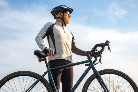 Bearded man cyclist stands with a bike against the blue sky. cycling and health hobbiesの写真素材