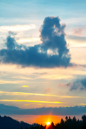 Colorful clouds in the sky at sunset against the backdrop of a mountainous forest area.の写真素材