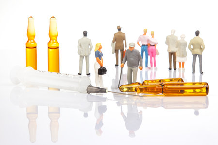 miniature people. man and woman stand near medical ampoules and a syringe. concept of vaccination and medical treatment of people lives in society.の写真素材