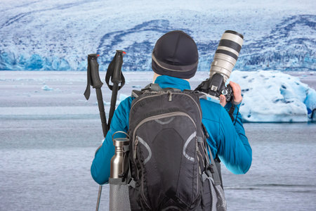 male tourist photographer with a backpack looks at the beauty of nature in the mountains. nature...