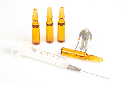 miniature people. man stand near medical ampoules and a syringe. concept of vaccination and medical treatment of people lives in society.の写真素材