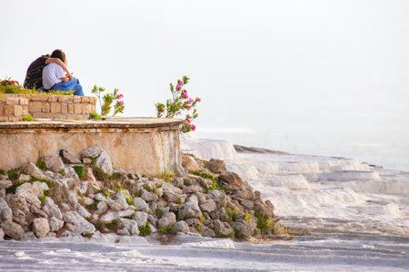 man and a woman sit against the backdrop of travertines in Pamukkale, Turkey. geology and mineral rockの写真素材