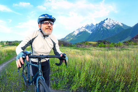 bearded man cyclist rides a bike on a road in nature. sports, hobbies and entertainment for healthの写真素材