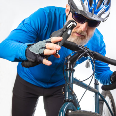bearded man cyclist in sunglasses holds a sports bike in his hands on a light background. Sports and...