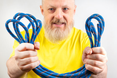 strong colored rope for climbing equipment in the hand of a bearded man in a yellow T-shirt on a...