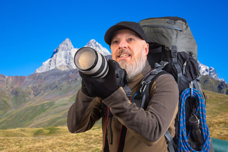 bearded man tourist photographer with a backpack photographs the beauty of nature in the mountains. nature hikes in the mountainsの写真素材