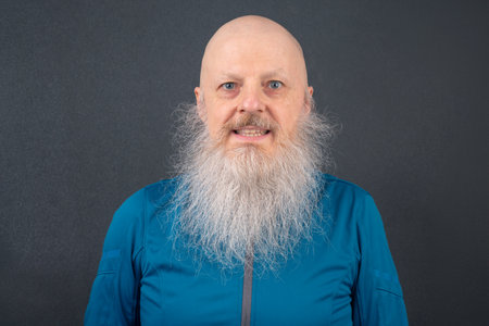portrait of a happy bald man with a large gray beard on a dark gray backgroundの写真素材