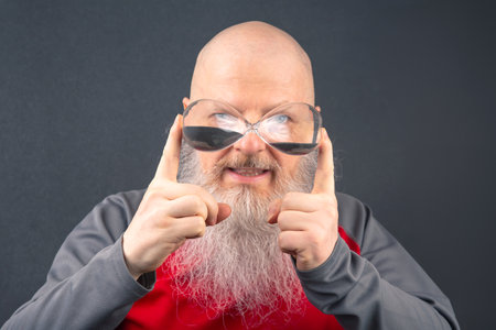 bald man with a large white beard holds an hourglass in his hands. concept of fluidity of life time