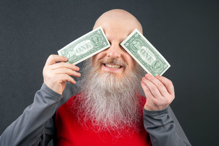 bald man with a large white beard holds a dollar in his hands. financial economics concept. poverty...