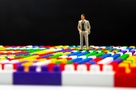 miniature people. figure of a man stand near the colored plastic blocks of the game constructor....