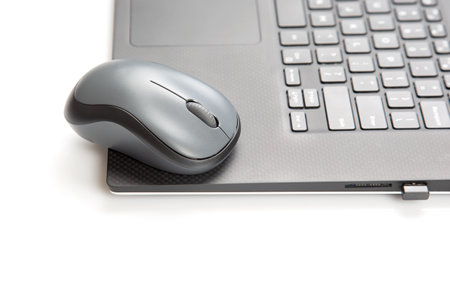 Computer wireless mouse next to a laptop on a white table close-up. electronic personal industry