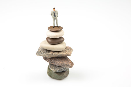 miniature people. the figure of a man stands on top of the stones. concept of achievements in life and success in business.の写真素材