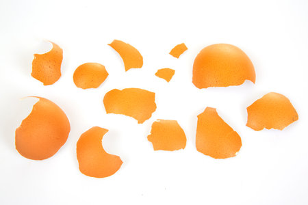 Two brown eggs cracked open with fragments on a white surface, blending warmth and texture in a...