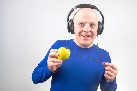bald man with headphones listens to music through a yellow player. Metaphor and concept of vitamin benefits in music and soundの写真素材