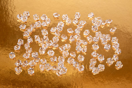 Close-up of faceted clear crystals on a reflective golden surface, capturing the essence of luxury and sophistication with a warm, radiant glow.の写真素材