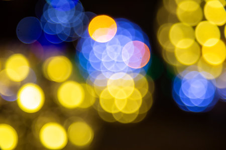 Abstract bokeh of golden and multicolored lights on a dark backdrop, evoking a magical, festive mood with a dreamy, out-of-focus glow.の写真素材