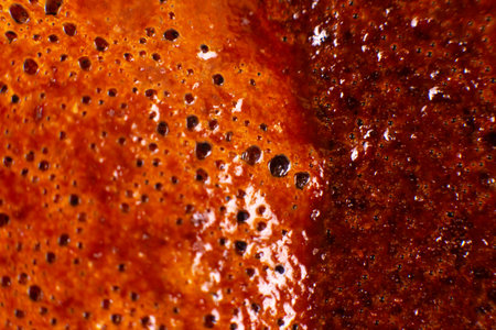 Macro close-up of frothy coffee crema with golden-brown bubbles, showing rich texture and reflective surfaces. Perfect for coffee lovers, beverage ads, or food photographyの写真素材