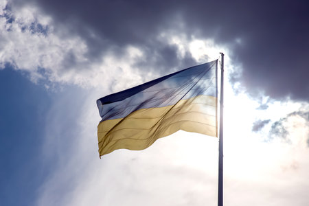 The national flag of the country of Ukraine against the background of the sun and blue sky....